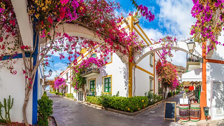 Whitewashed houses on a street in Puerto de Mogan, festooned with Bougainvillea flowers